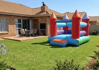 Colorful inflatable bounce house on a lush green lawn in a backyard. Perfect for children's outdoor.