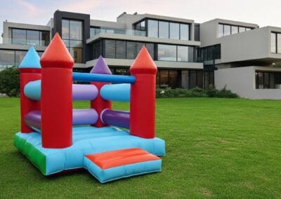 Colorful inflatable bounce house on a lush green lawn in front of a modern house.